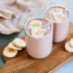 two chocolate banana smoothies on a wood board