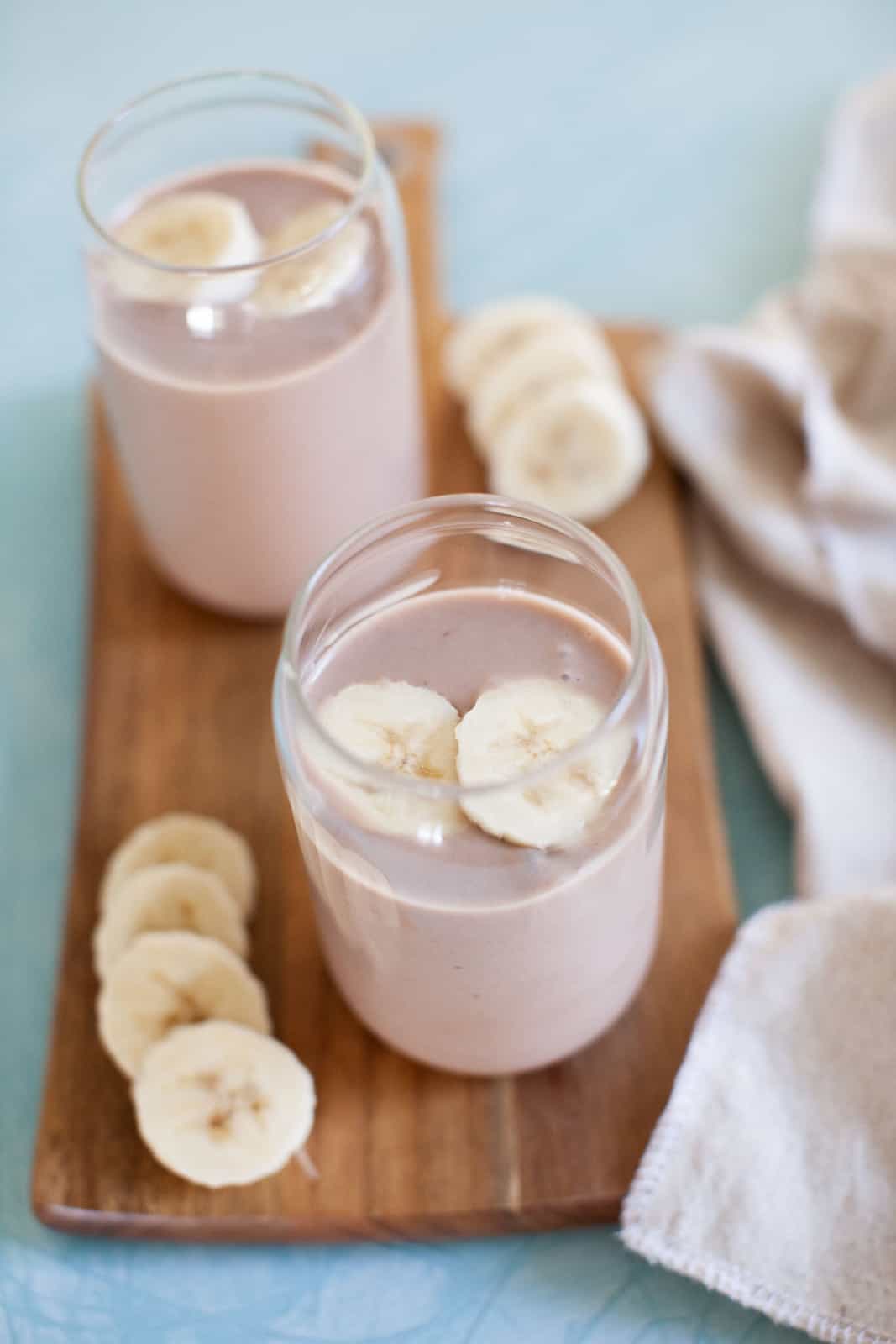 Two chocolate smoothies with frozen banana slices on top.