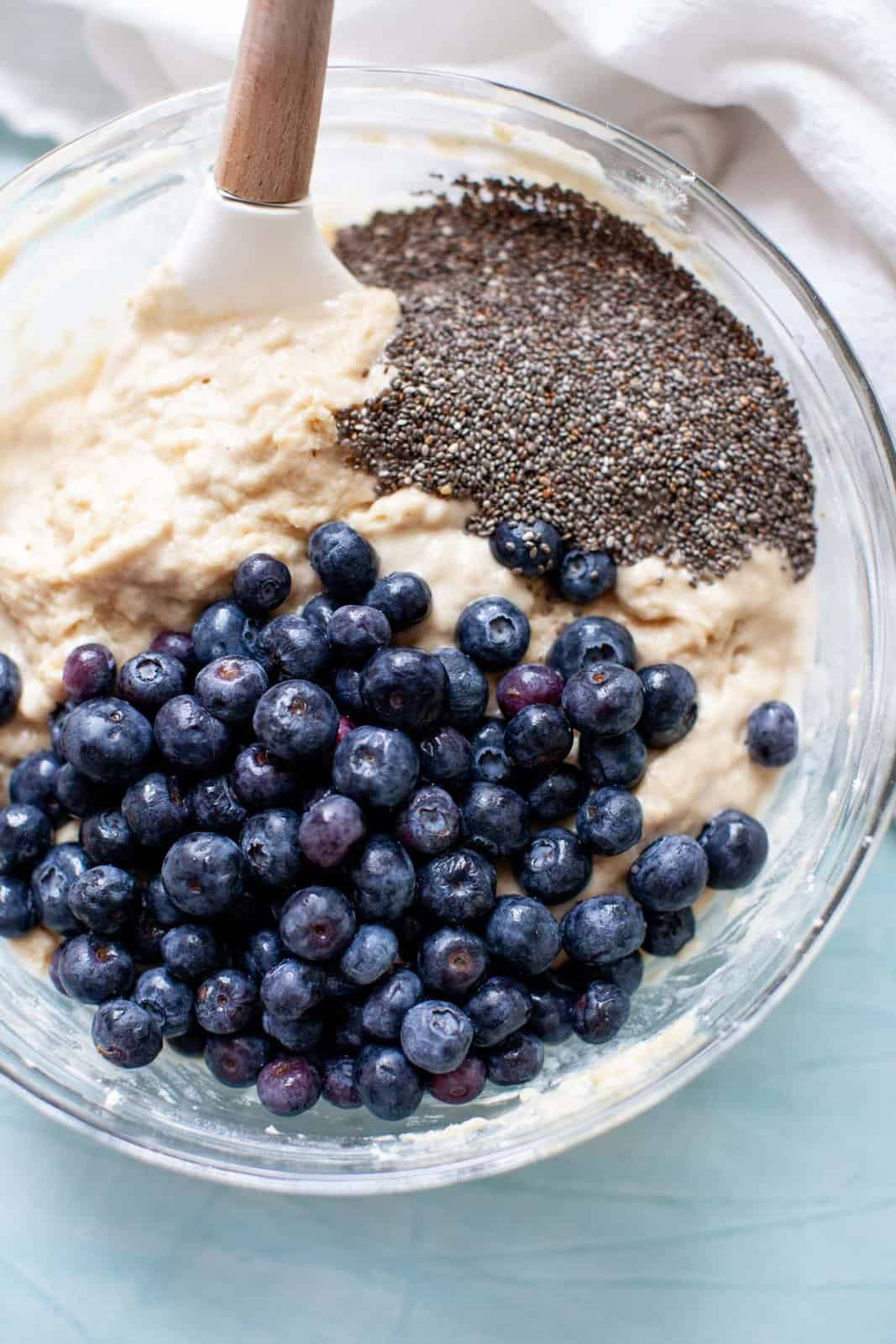 mixing chia seeds and fresh berries into muffin batter