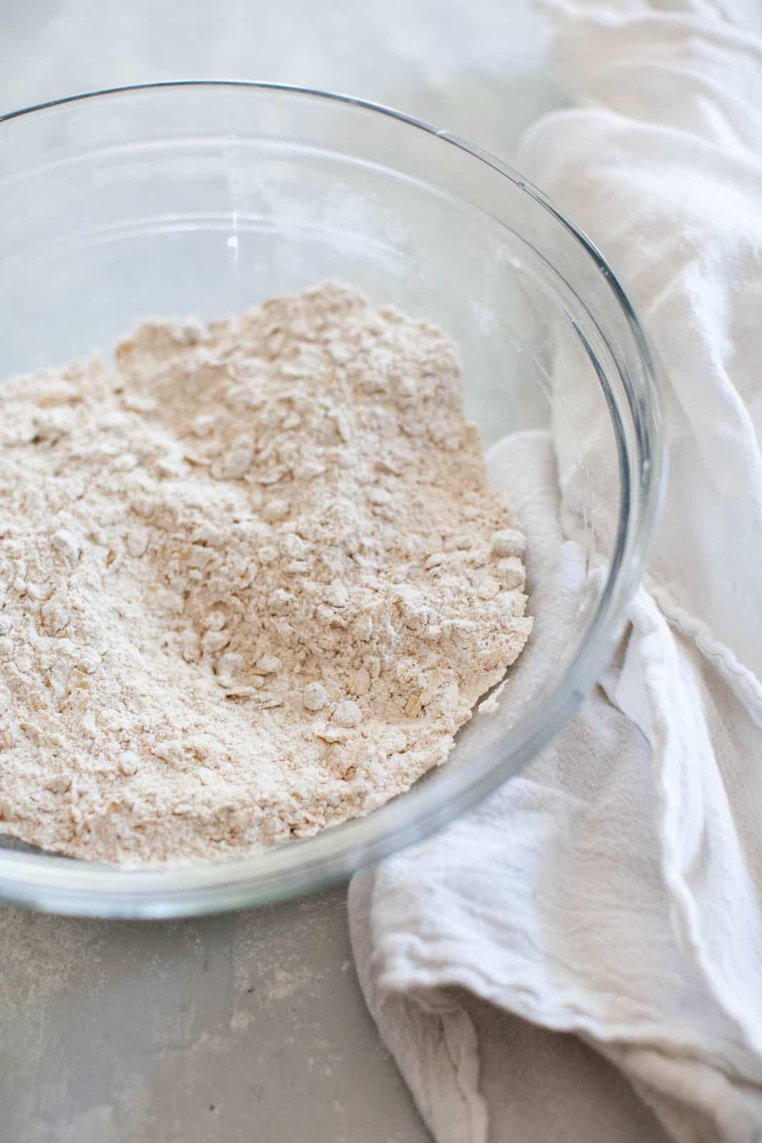 A bowl filled with a dry mixture of all-purpose flour, rolled oats, sugar, and spices.