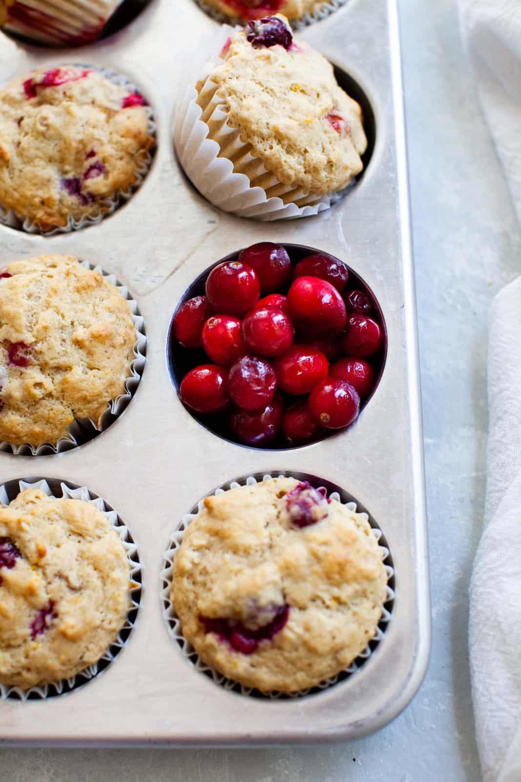 A baking pan of freshly baked holiday muffins with red berries.