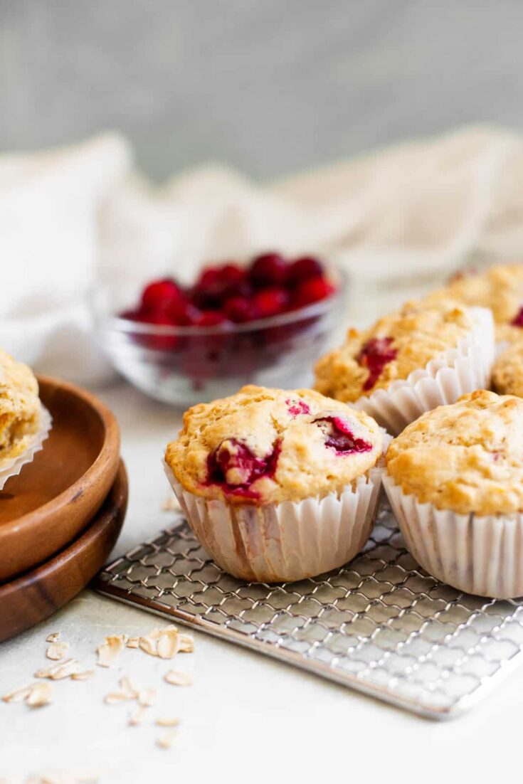 Freshly baked muffins on a cooling rack next to small wooden serving plates.