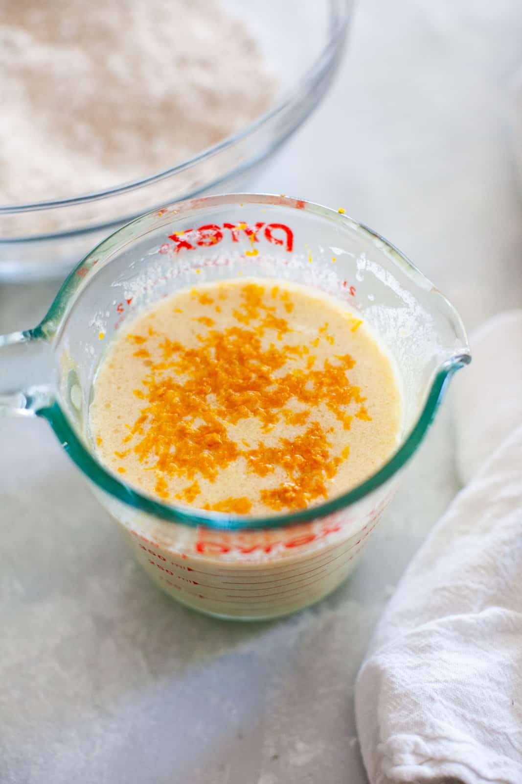 Orange zest in a glass measuring cup with milk.