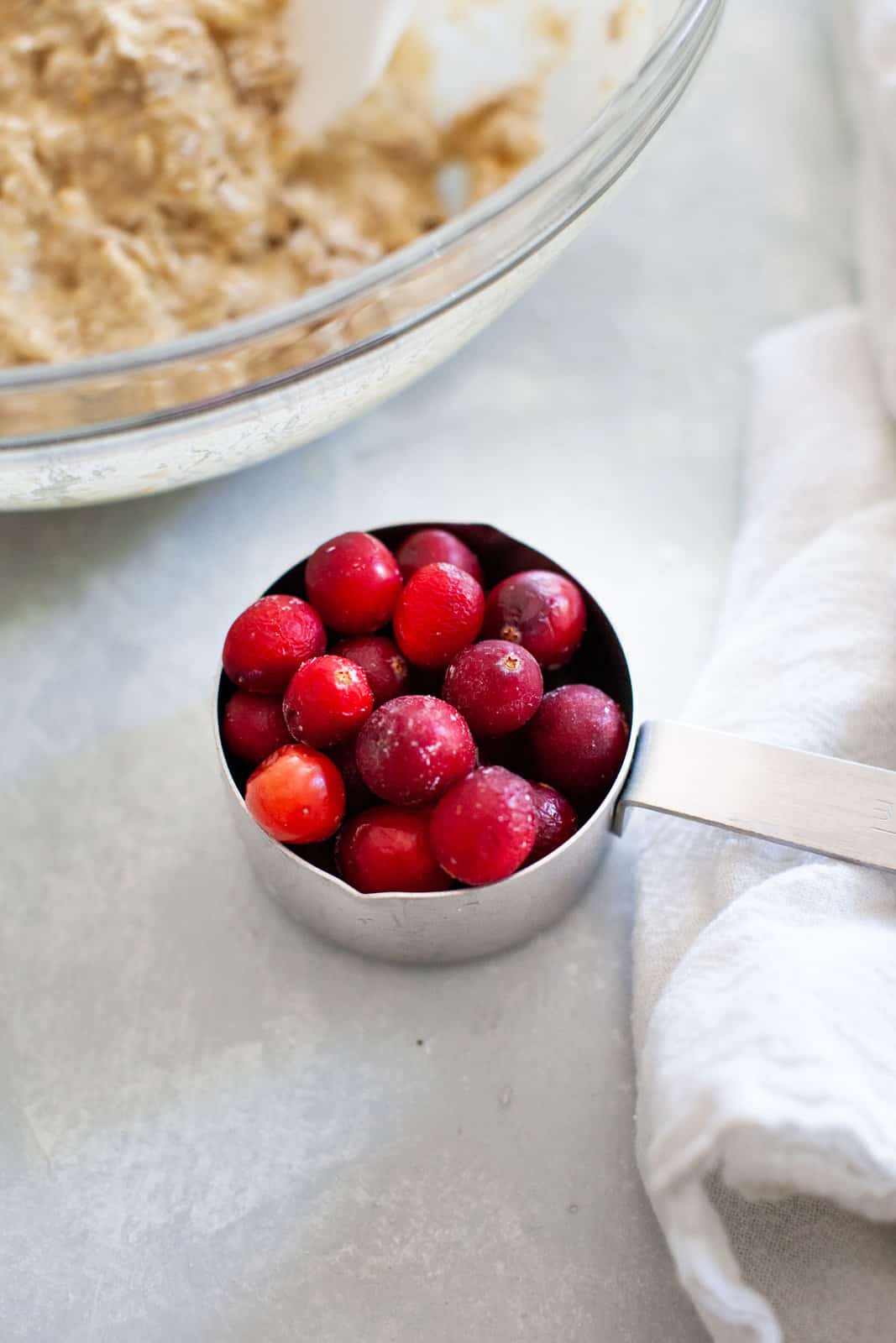 Overhead view of fresh red berries in a metal measuring cup.
