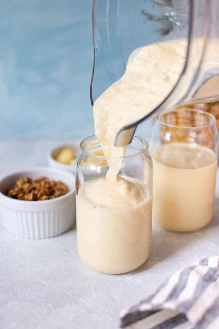 Pouring pineapple smoothie into a glass.