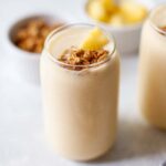 a sprinkle of granola on top of a pineapple smoothie.