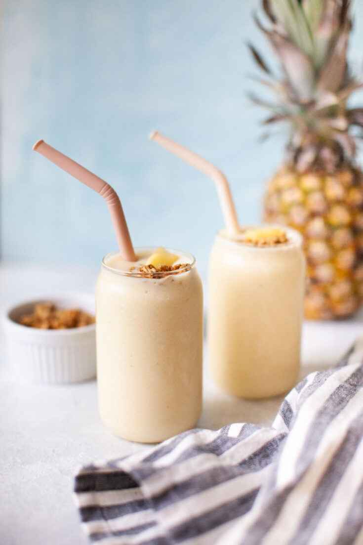 Two pineapple banana smoothies with straws.