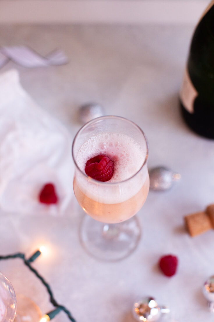 a raspberry on top of a champagne cocktail.