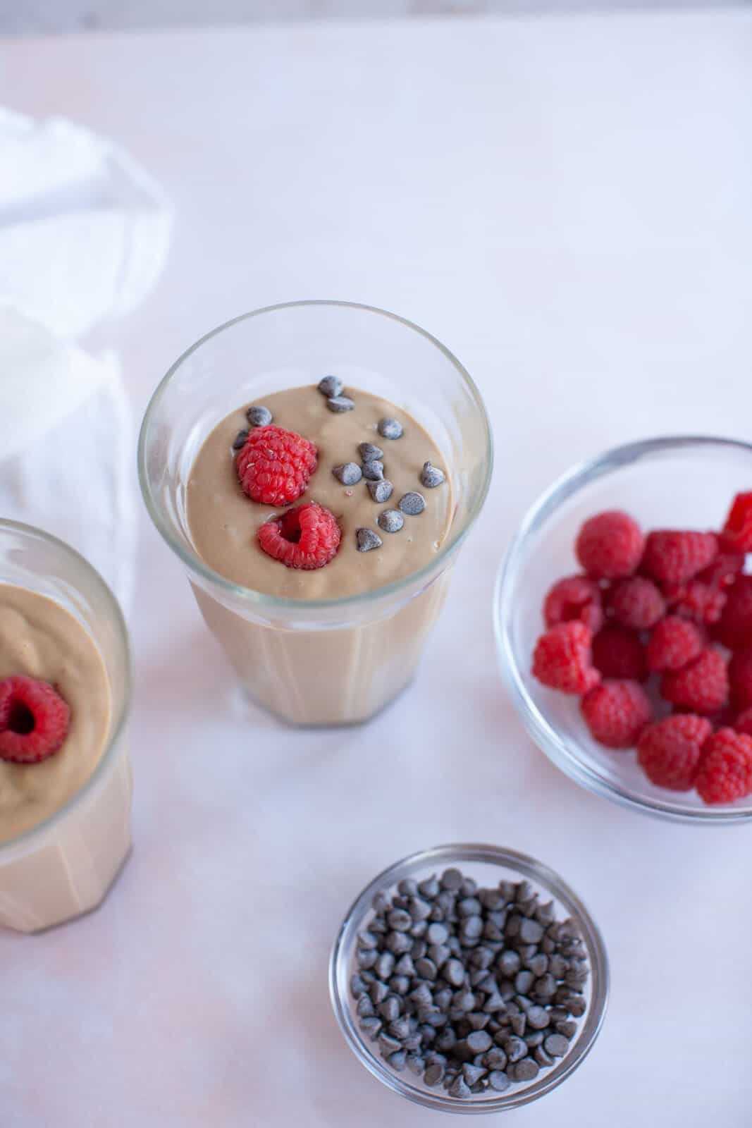 a chocolate smoothie next to bowls of berries.