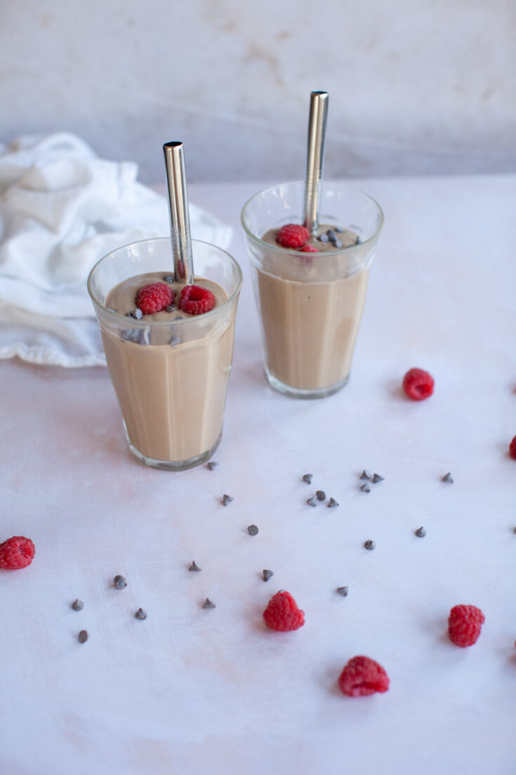 chocolate chips next to a pair of chocolate smoothies.