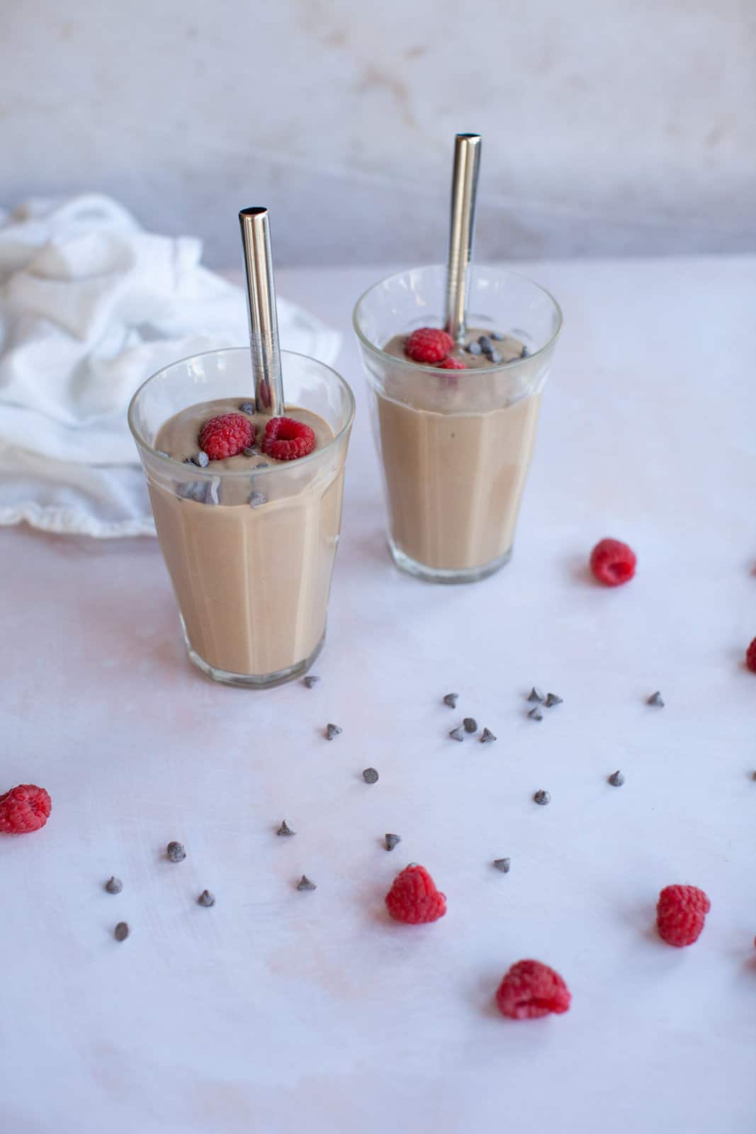 chocolate chips next to a pair of chocolate smoothies.
