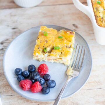 a fork, berries and egg caserole on a gray plate