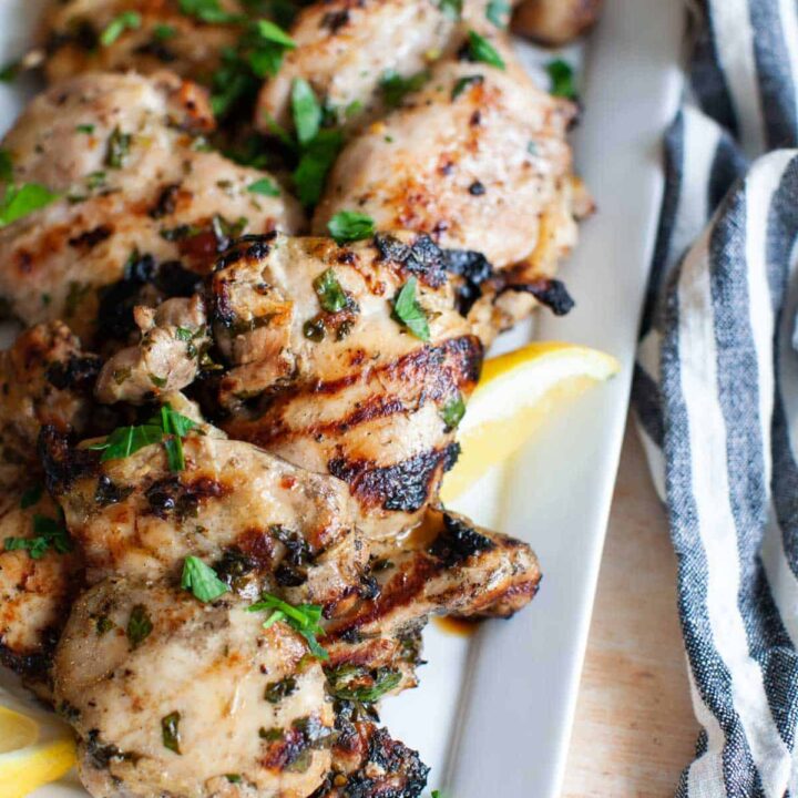 grilled lemon chicken thighs on a white plate