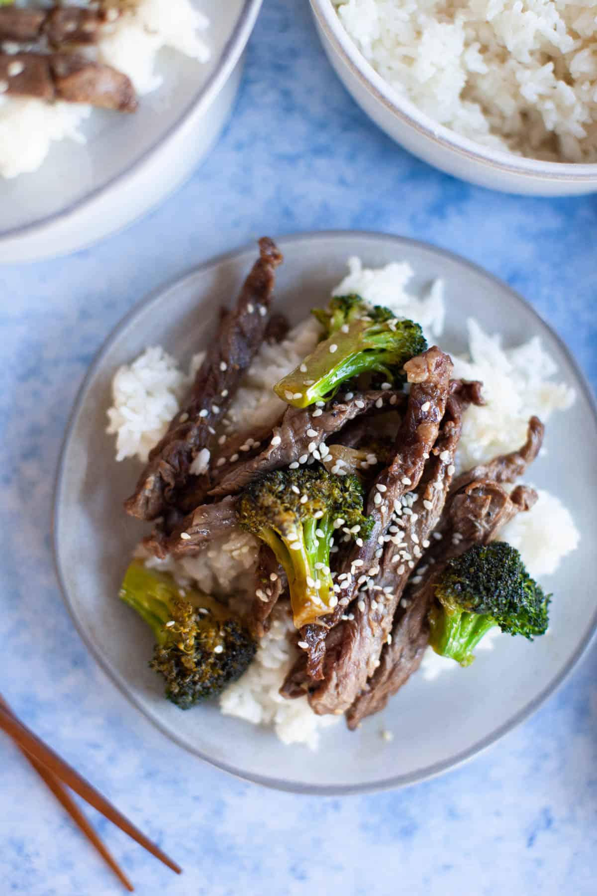 a plate of rice with steak and broccoli on top