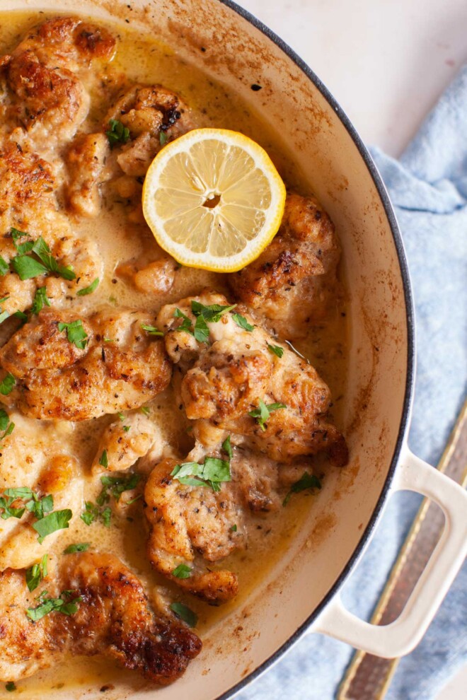 lemons, parsley and chicken in a white pan.