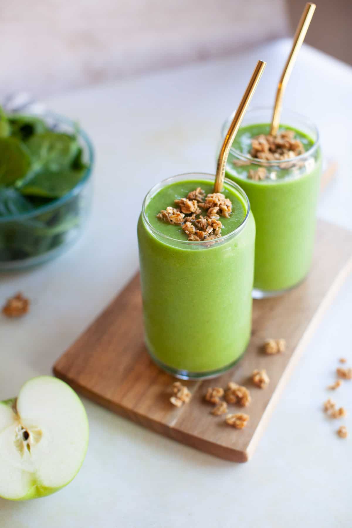 granola on top of a green smoothie with a copper straw