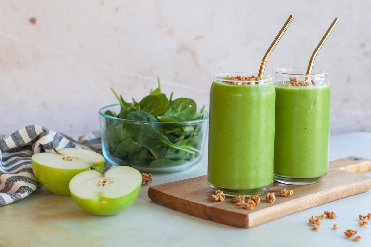 two green apple smoothies on a wooden board