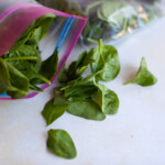 An open Ziploc bag with spinach on the counter.
