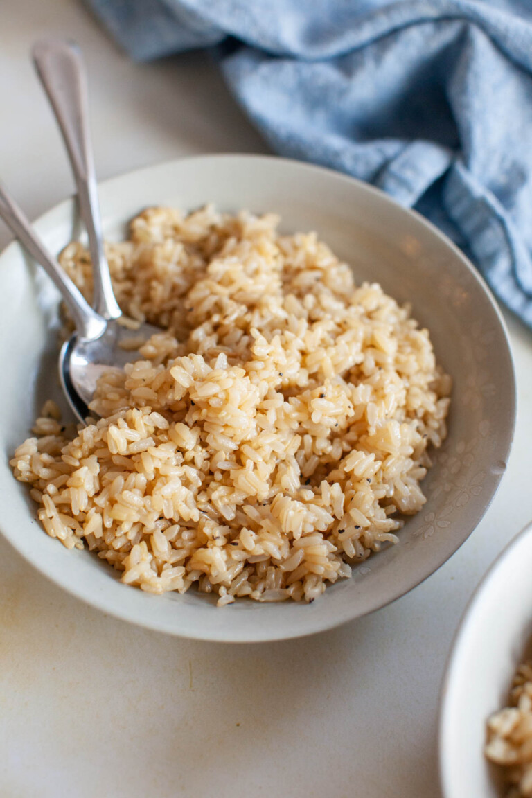 A bowl of brown rice in a bowl, with two spoons