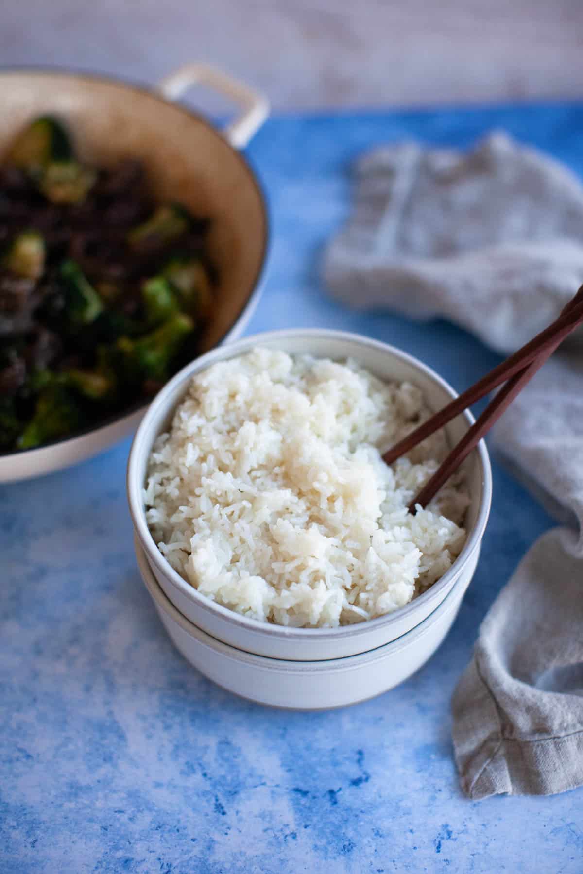 Instant Pot jasmine rice in a small white bowl with chopsticks.