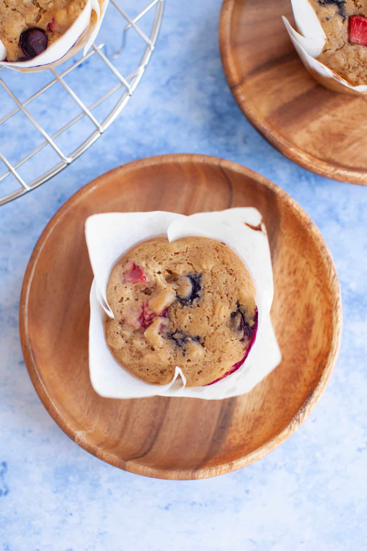 muffins on wooden plates on a blue counter.