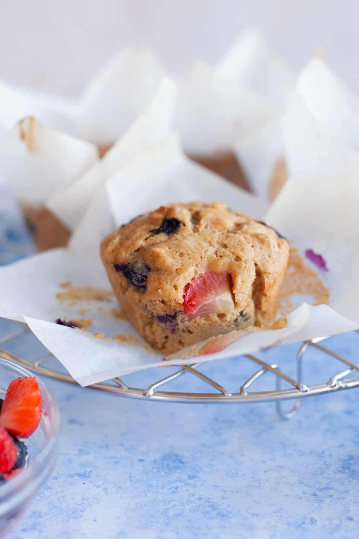 muffins with three kinds of berries on a cooling rack.