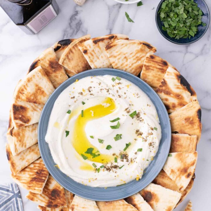 A bowl of whipped feta dip surrounded by pita bread.