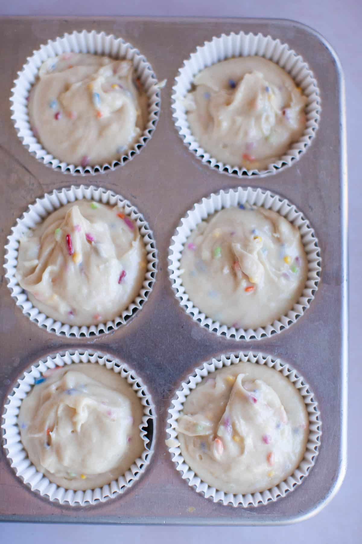 confetti cupcake batter in a muffin tin.