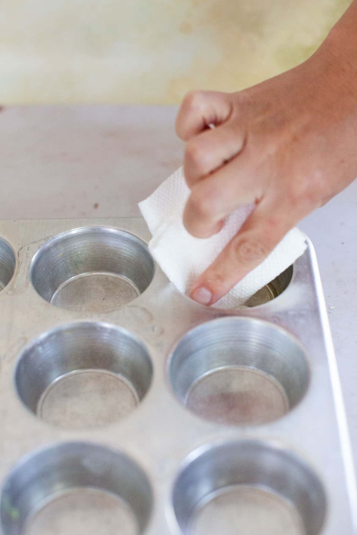 Paper towel wiping a muffin tin.