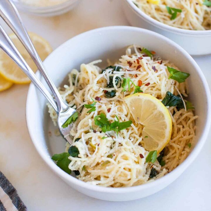 A white bowl full of lemon ricotta pasta, with two forks in the bowl.
