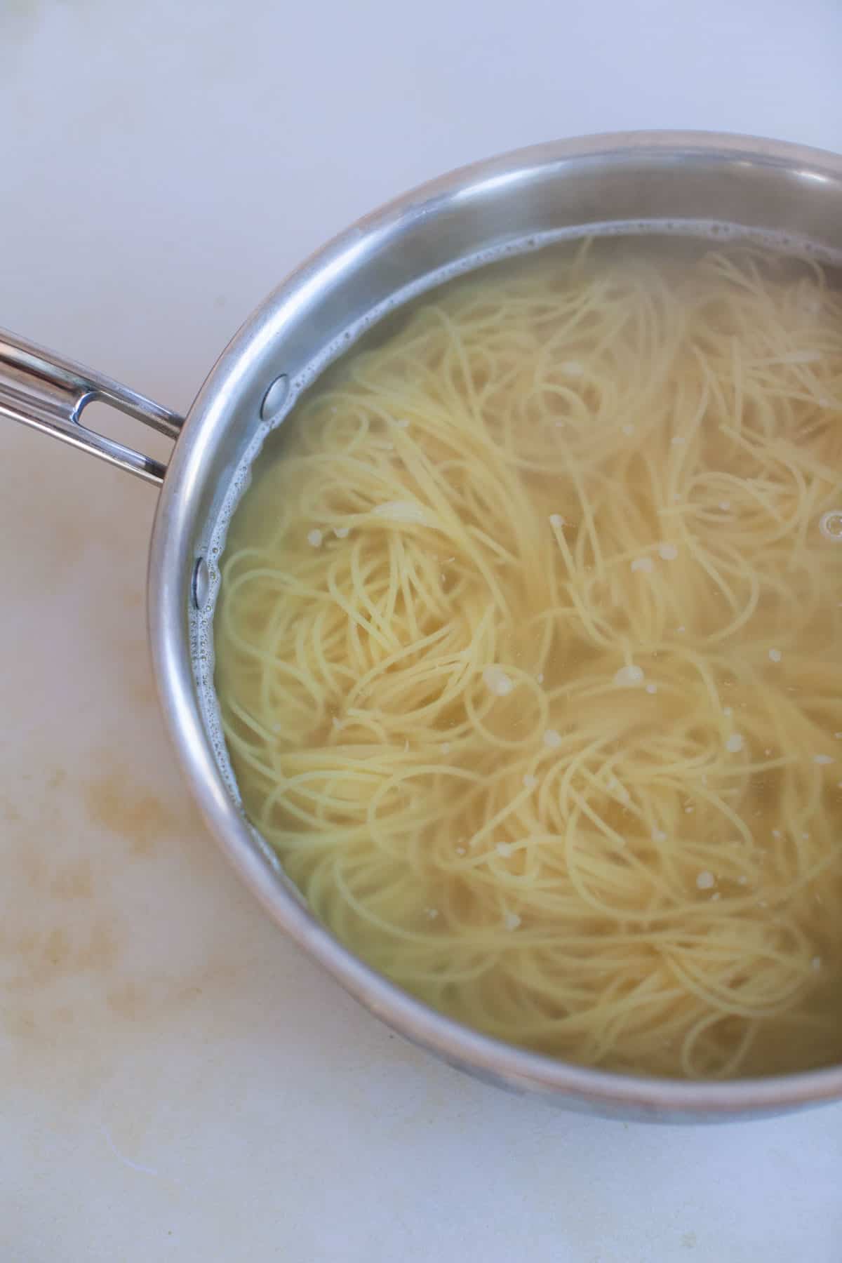 Angel hair pasta being cooked in a pot of water.