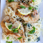 overhead of chicken piccata topped with lemon slices and parsley on a bed of pasta