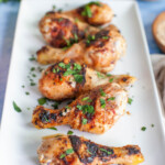 Grilled drumsticks arranged on a rectangular serving dish garnished with parsley.