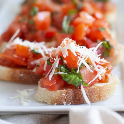 Close-up photo of pieces of bruschetta on a rectangular serving dish.