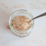 Homemade burger seasoning in a small, glass mason jar with a spoon.