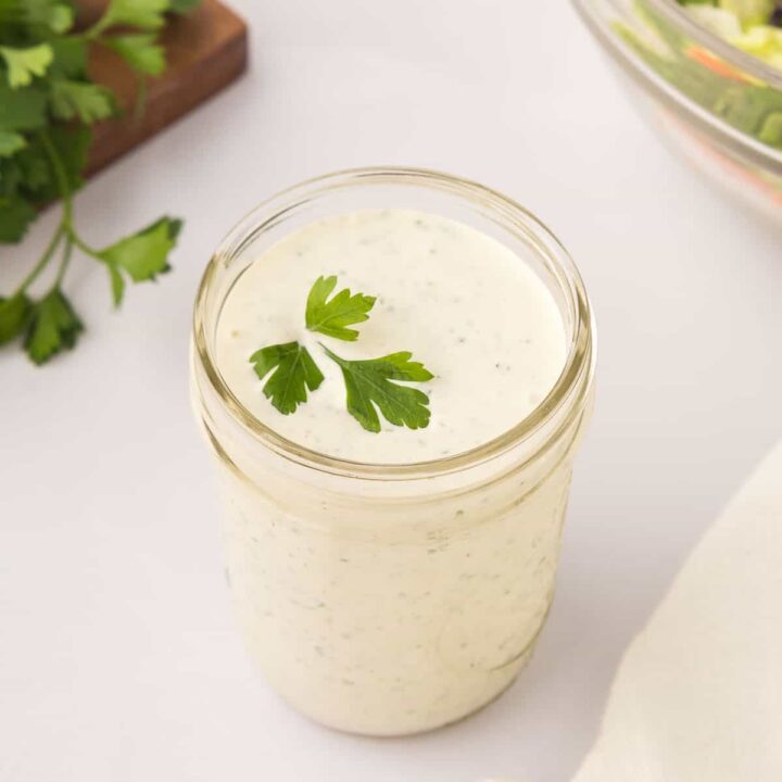 Homemade ranch dressing with parsley garnish in a mason jar.