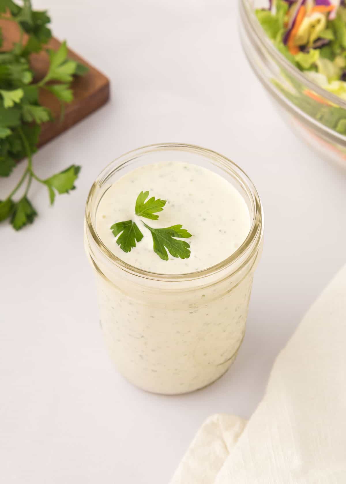 Homemade ranch dressing with parsley garnish in a mason jar.