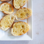 Crostini on a white platter, on a marble countertop