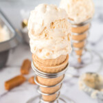 Angled overhead photo of two sugar cones in wire cone holders filled with two scoops of salted caramel ice cream.