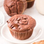 Close up photo of chocolate muffin on a small, white plate.