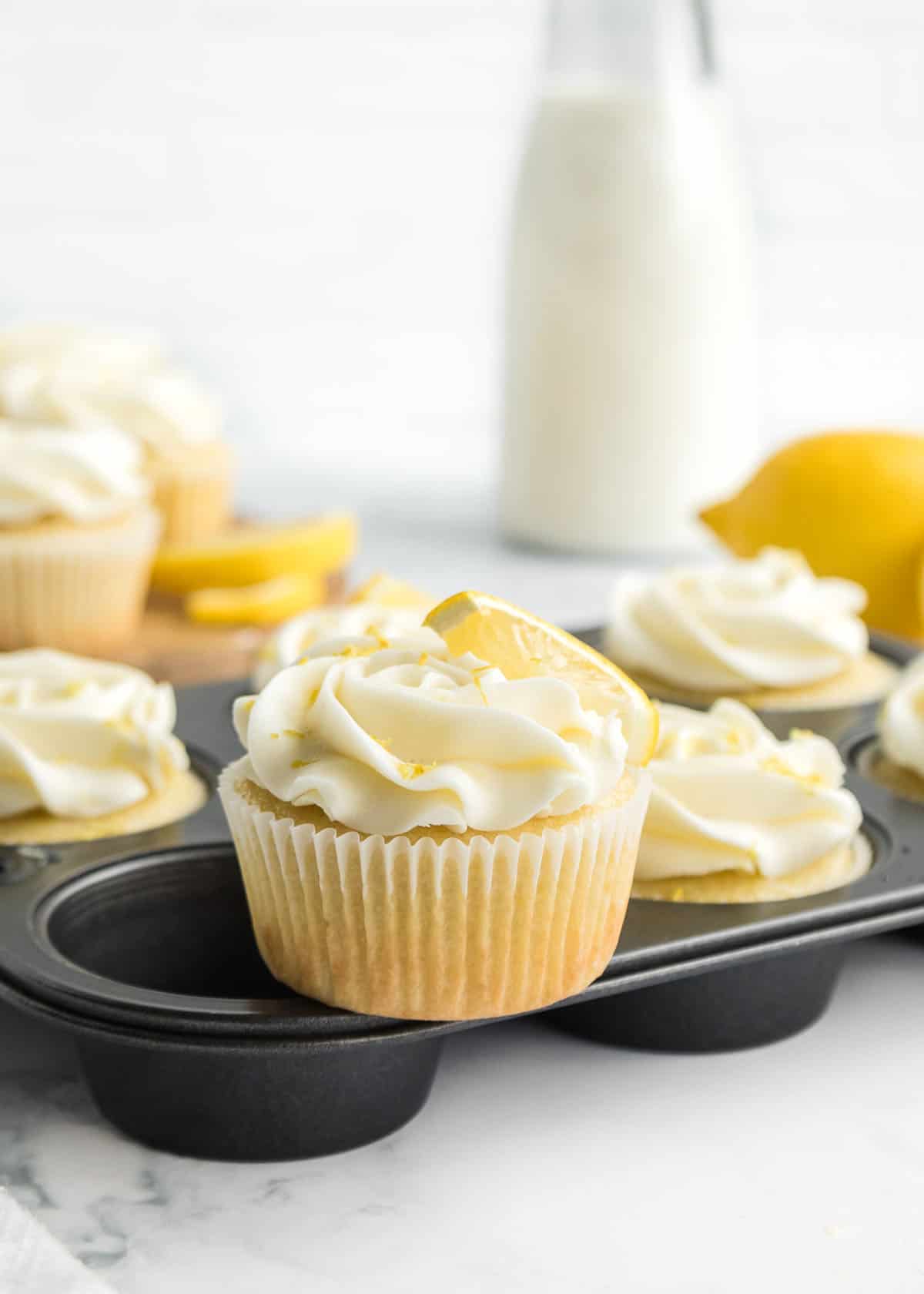 One lemon cupcake with lemon slice garnish placed on top of the muffin tin.