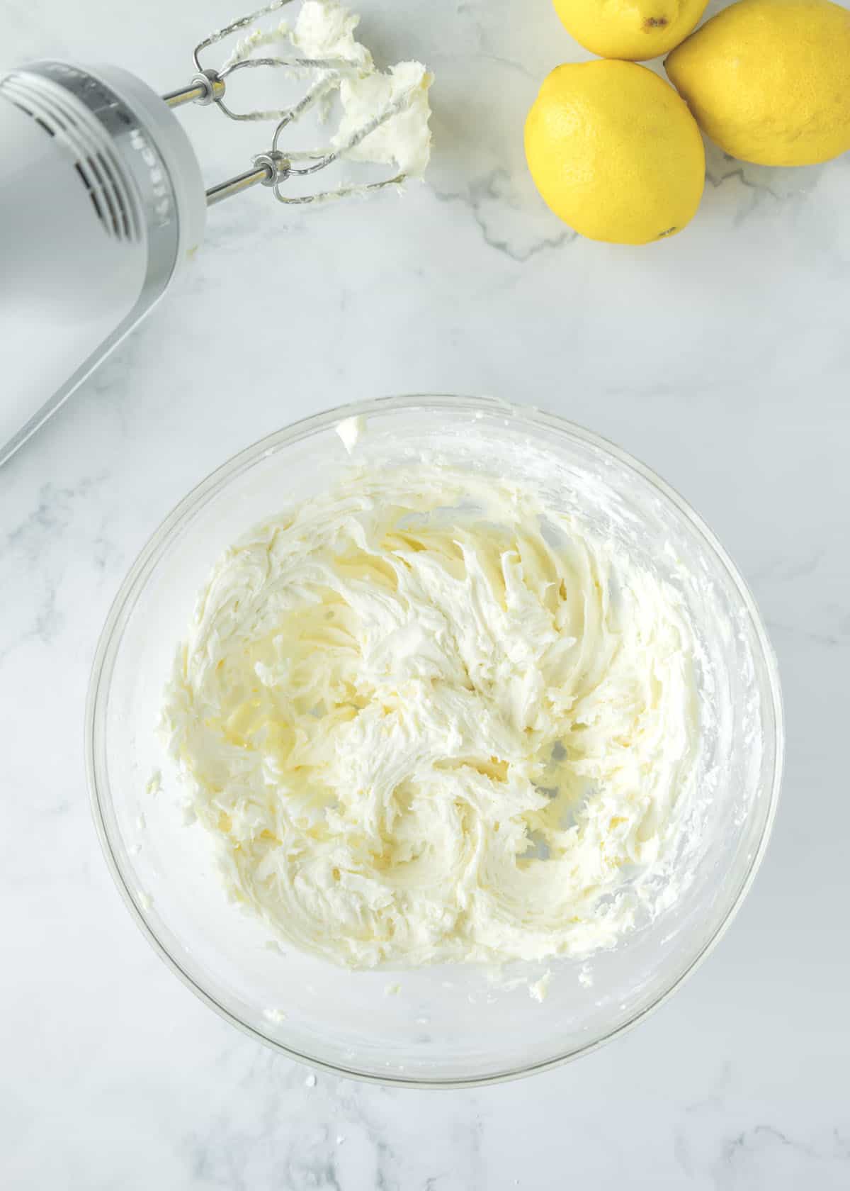 Heavy cream is added to the powdered sugar, lemon zest, butter, and vanilla extract mixture.