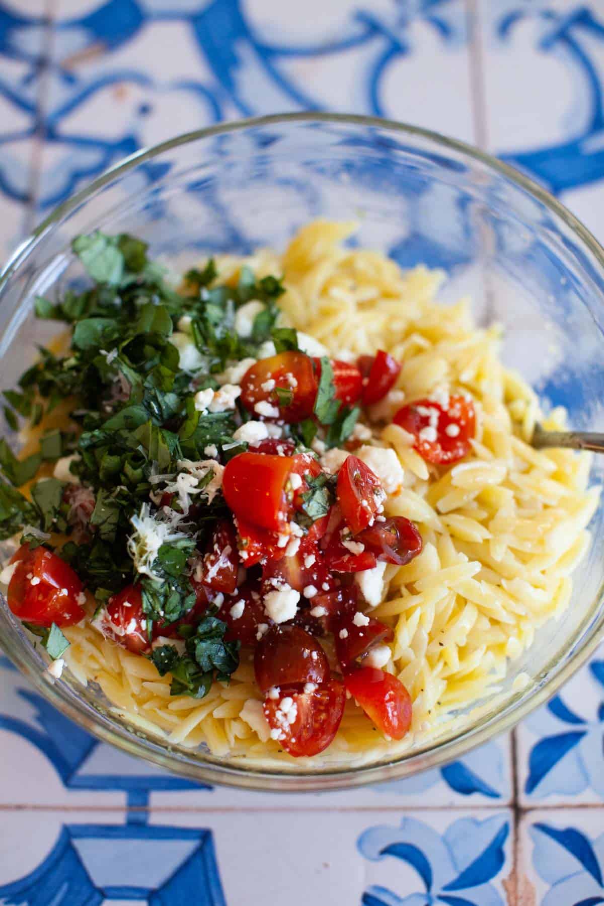 Basil, feta, and tomatoes added to orzo with dressing.