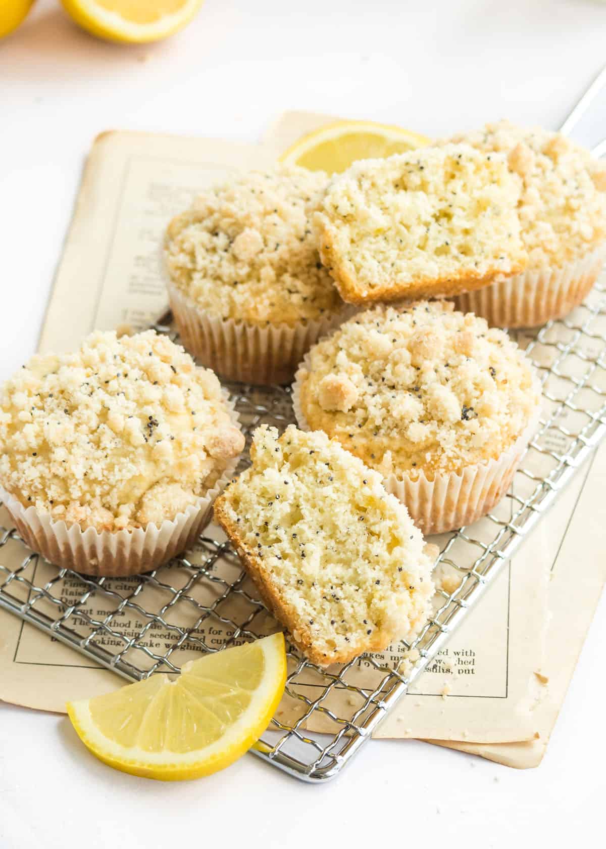 Close-up photo of lemon poppy seed muffins on a rectangular wire serving platter. One muffin cut in half on top of the other muffins.