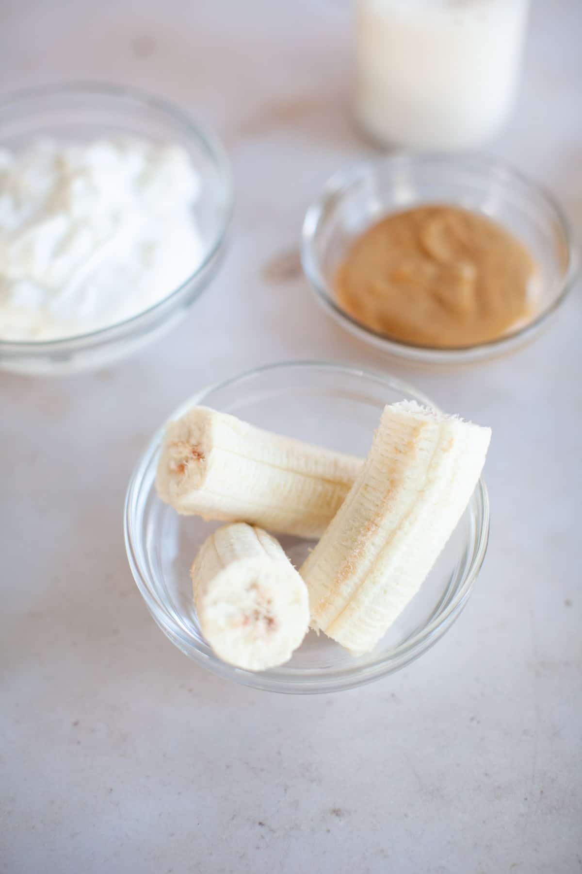 Frozen banana, peanut butter, and Greek yogurt in glass bowls