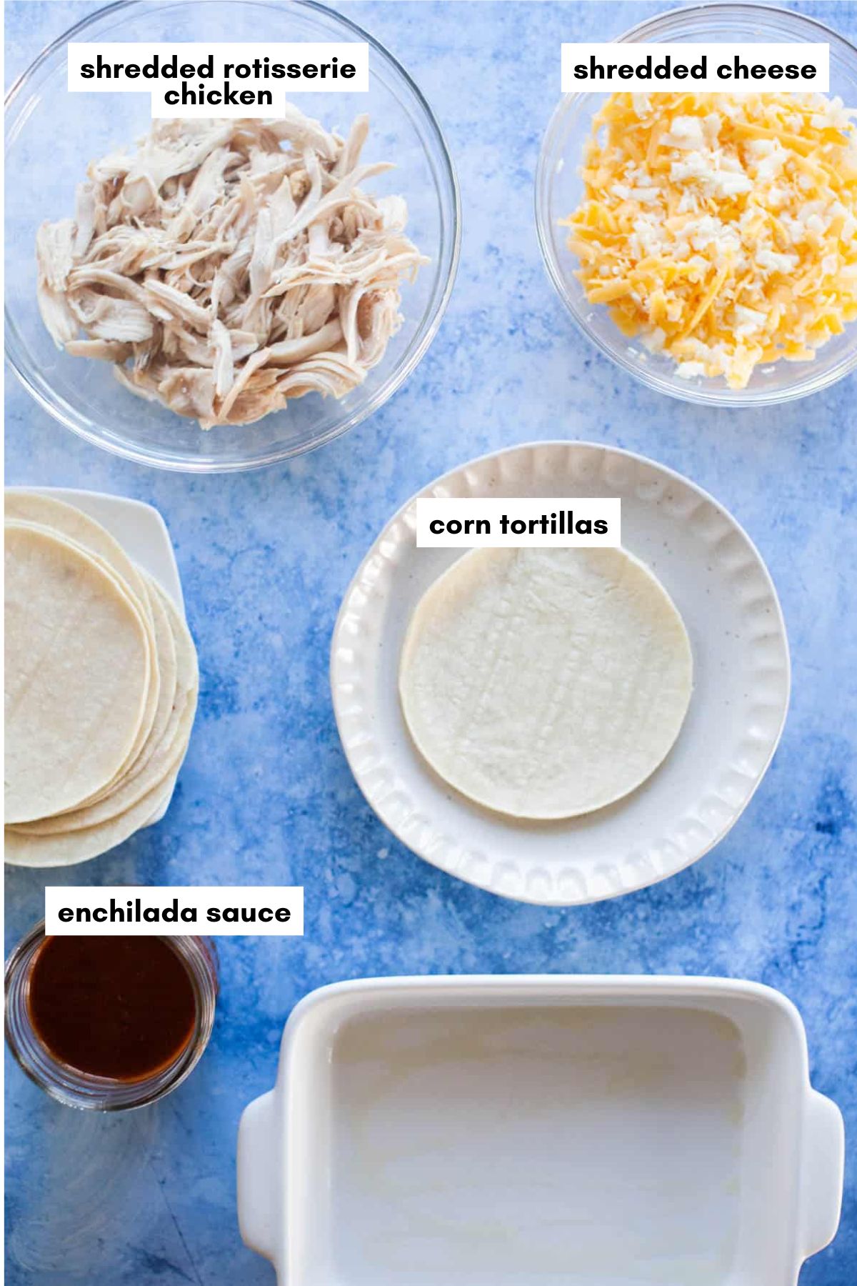 Ingredients for rotisserie chicken enchiladas, including shredded chicken, cheese, corn tortillas, enchilada sauce, and an empty baking dish.