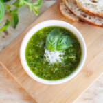 pesto in bowl on top of wooden cutting board with bread