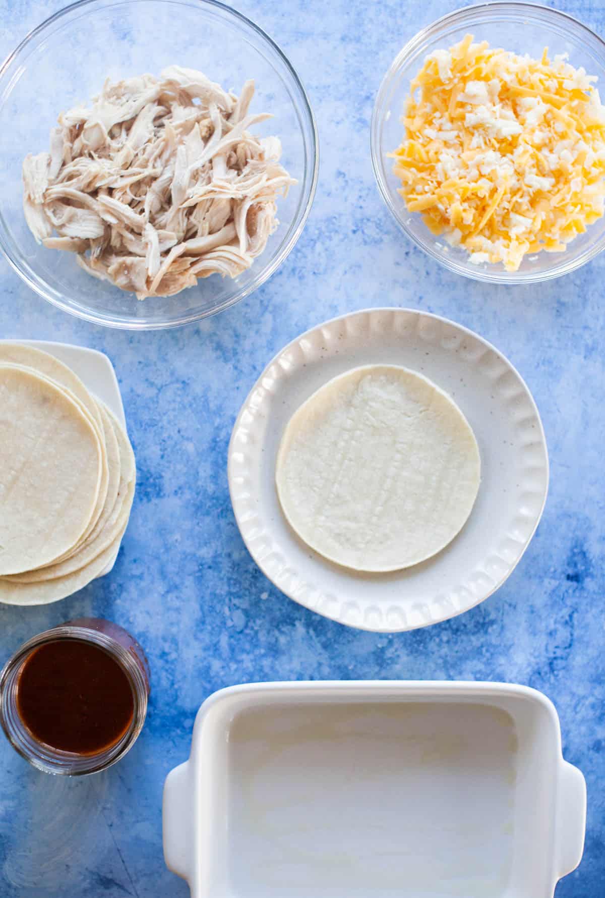 Chicken enchilada ingredients separated into individual bowls and plates.