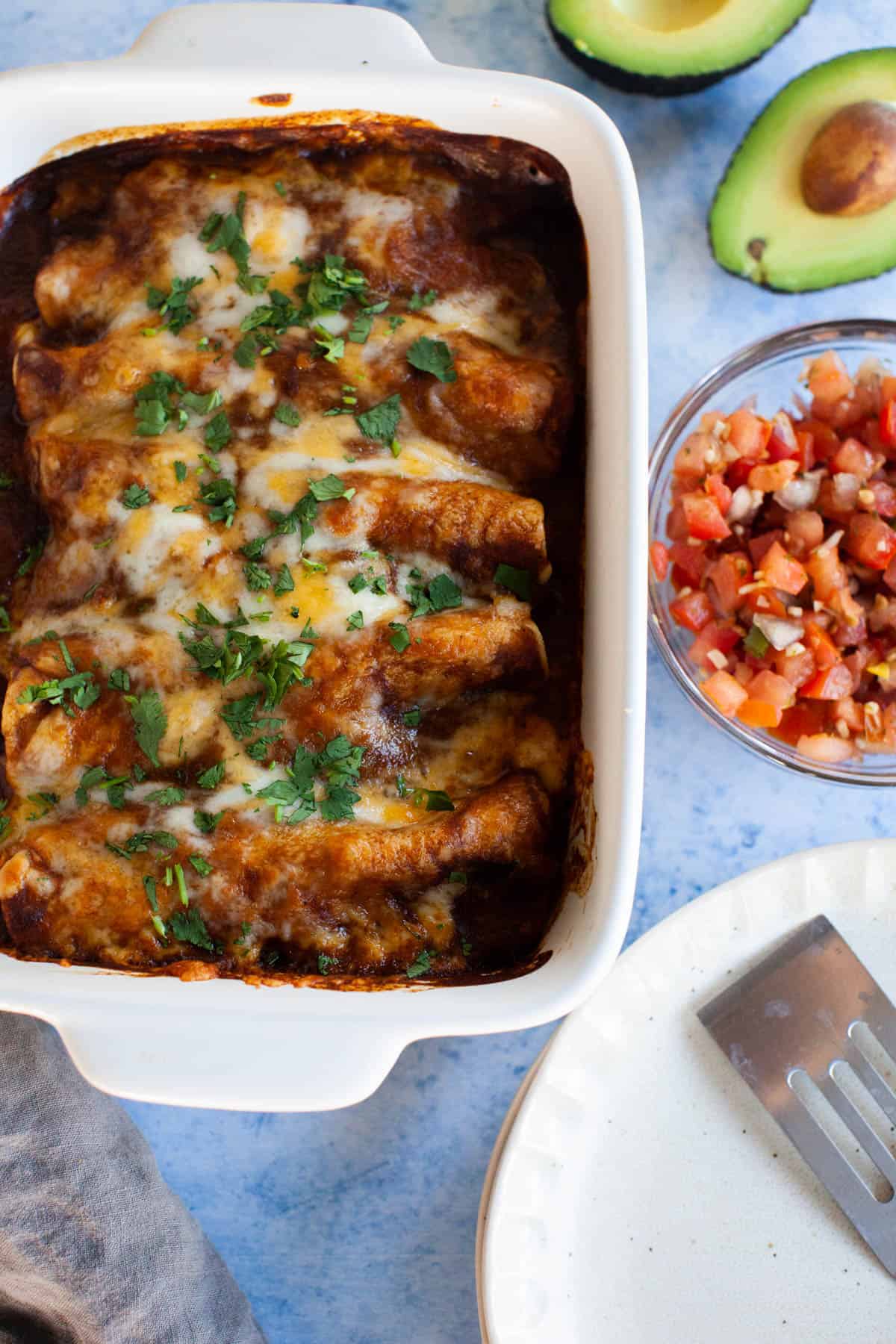 enchiladas in red sauce in a white pan.