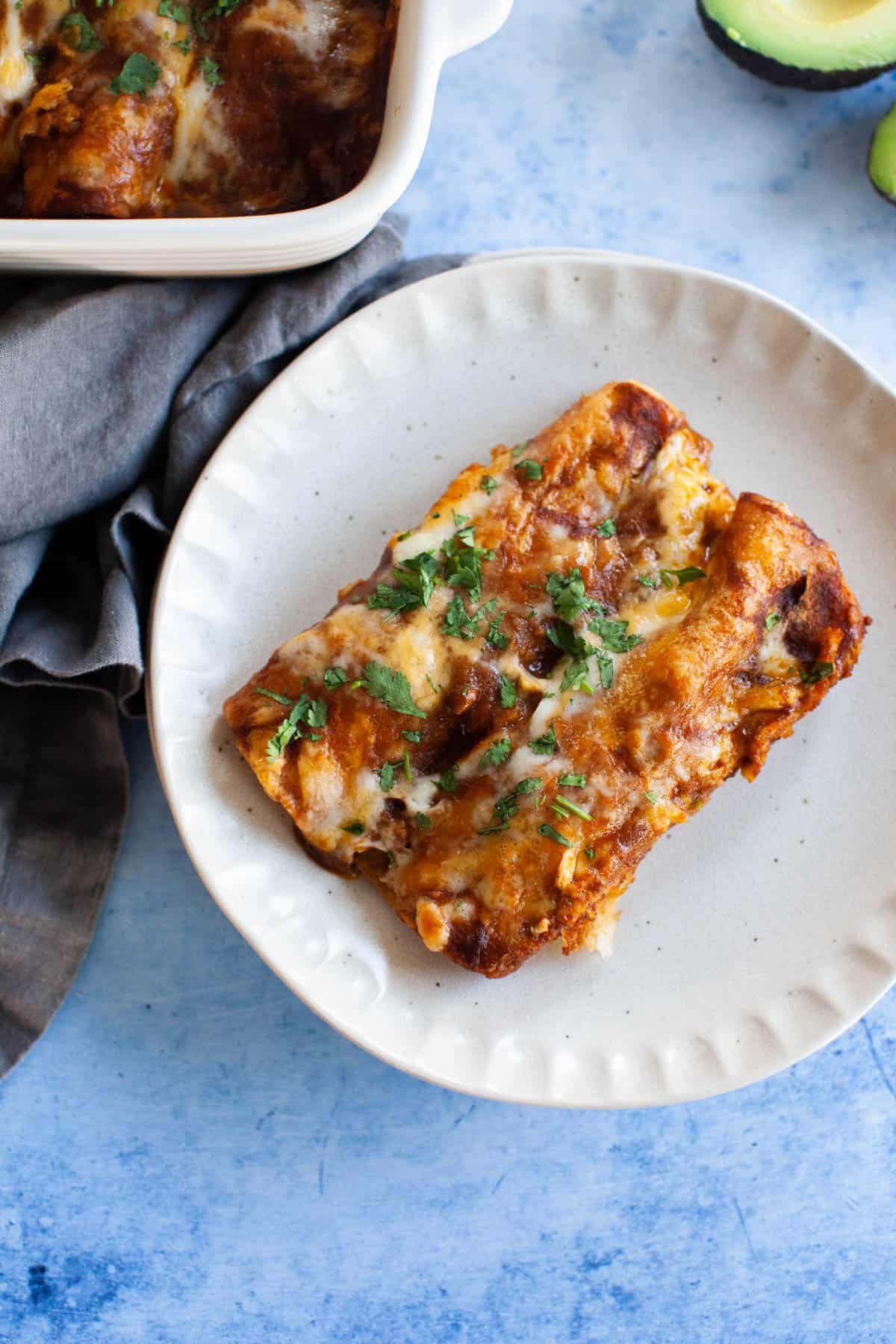 Close up photo of two enchiladas on a small, white plate.